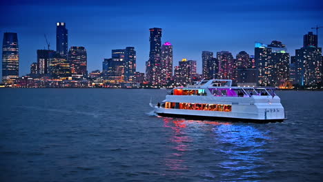 two-storied riverboat with people travels by the waterscape at dusk time. dazzling skyline of new york, usa at backdrop