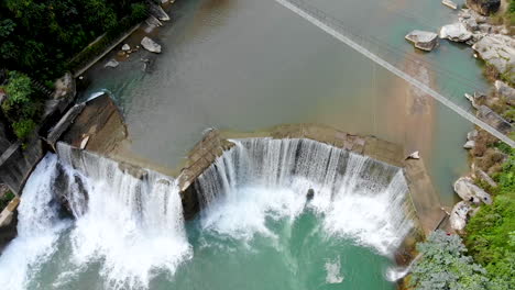 bird's eye view of large river turning into a huge waterfall in the mountains