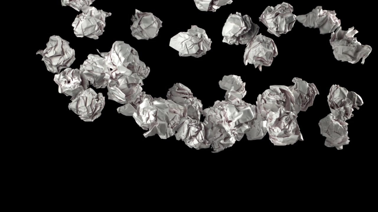 Palline di carta bianca accartocciata che cadono e scompaiono su sfondo nero