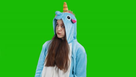 portrait of a cute young brunette girl in a beautiful unicorn costume on chrome key green background. upset, sad. animator in costume. unicorn pajamas. 4k video with alpha channel