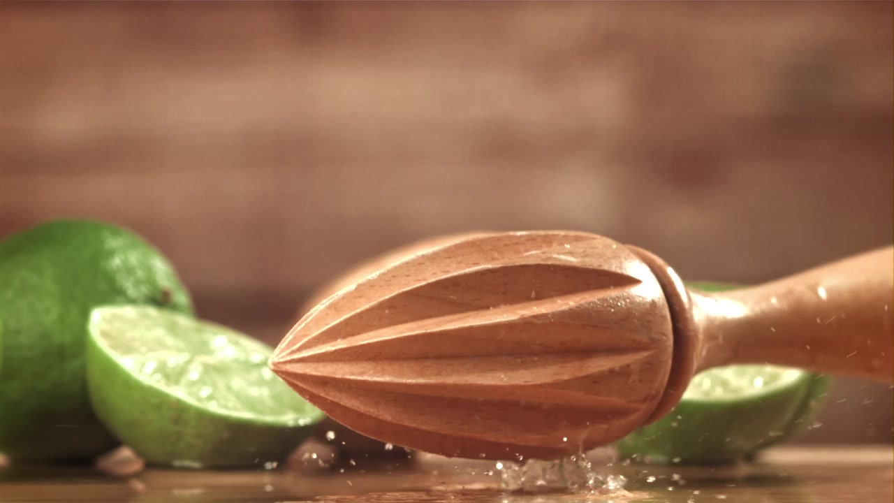 Spremiagrumi in legno che schizza succo di lime al rallentatore