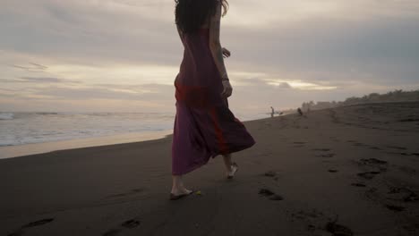 attractive woman wearing dress walking on the sandy shore barefooted