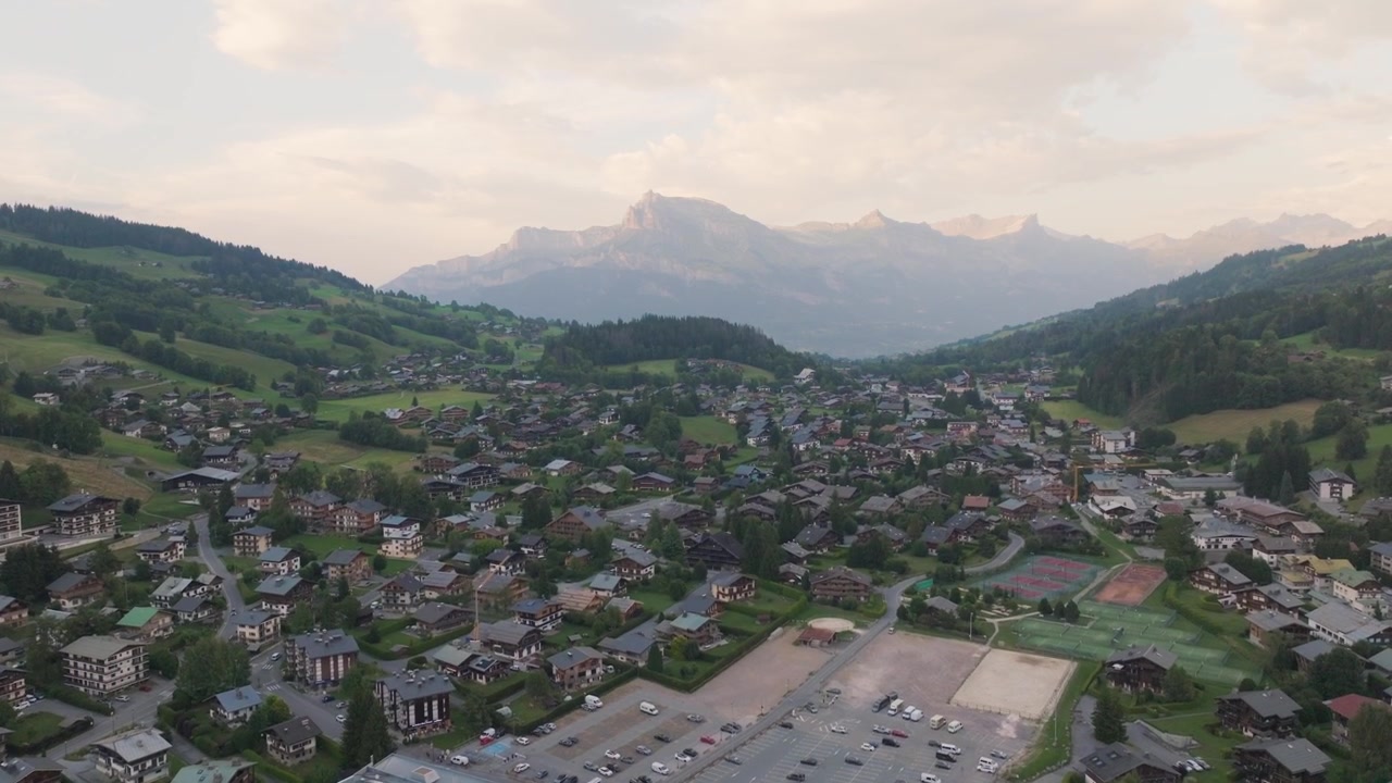 Luftaufnahmen mit Drohne von Megève, Frankreich, umgeben von den atemberaubenden französischen Alpen. Filmische Berglandschaften mit alpinen Wäldern, traditionellen Chalets, sanften Hügeln und spektakulären Panoramablicken.