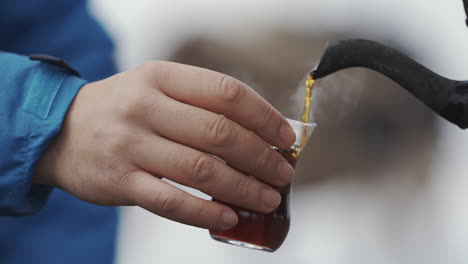 vista recortada de verter té en una taza de vidrio al aire libre