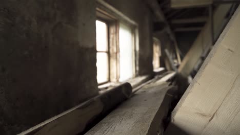 sunlight passing through glass window of an old shed with pile of timber inside. - wide shot