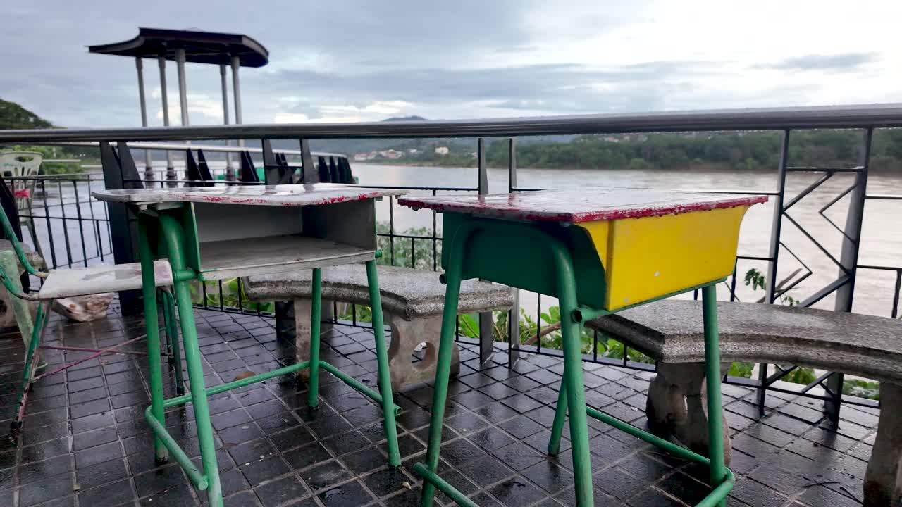 Outdoor tables and chairs overlook the riverfront in Chiang Khong Thailand on a cloudy day