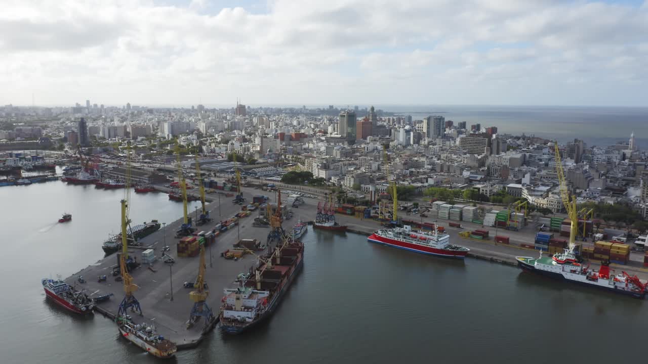 Uruguay capital city Montevideo. Forward moving aerial drone view from barrio Ciudad Vieja towards downtown, seen from above the port. Calm cloudy weather