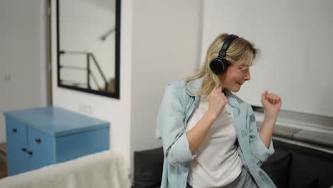 happy young woman dancing at home having fun listening to music wearing headphones