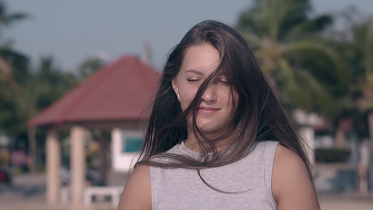 una chica sonriente trata de quitar el cabello de la cara en cámara lenta