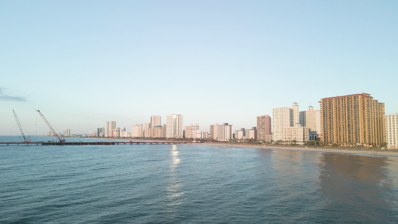 Aerial drone flyover above the Atlantic Ocean at Myrtle Beach, South Carolina, with beach skyline