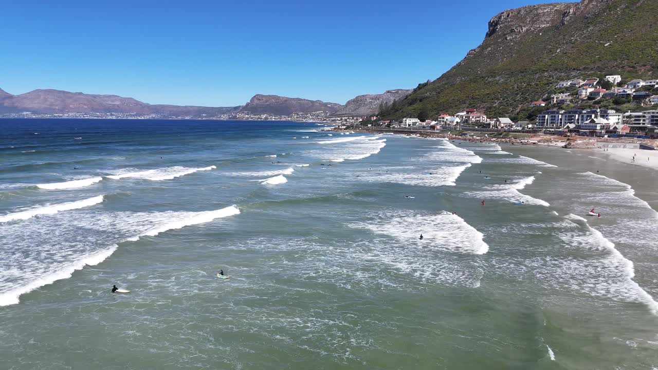 Drone flying just above the Atlantic Ocean waves with Cape Town visible in the distance, capturing the coastline and cityscape South Africa travel destination