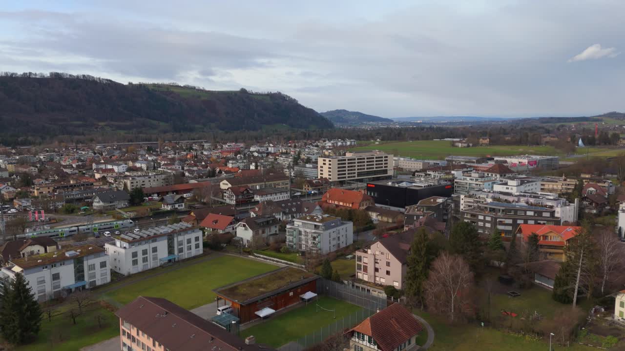 ciudad suiza con edificios y colinas en el fondo, día nublado, vista aérea