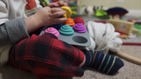 Un-Niño-Pequeño-Sentado-En-El-Suelo-Jugando-Con-Pastelitos-De-Juguete-De-Plástico