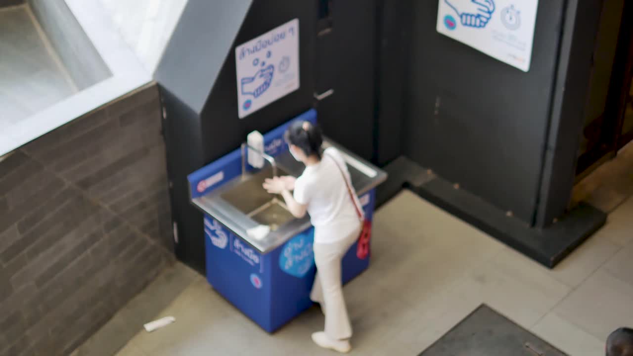 Woman Wearing Mask and Washing Hand Using Public Hand Sanitizer Unit During Coronavirus Epidemic