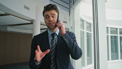 businessman complaining work cellphone conversation in hallway window closeup