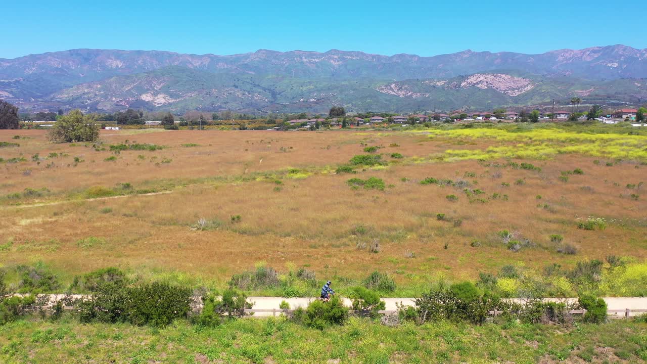 antena de un hombre montando su bicicleta con las montañas de santa barbara en el fondo cerca de carpinteria californa