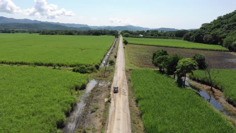 Car-driving-on-road-with-many-pit-holes-in-Mexican-suburbs-surrounded-by-agricultural-fields