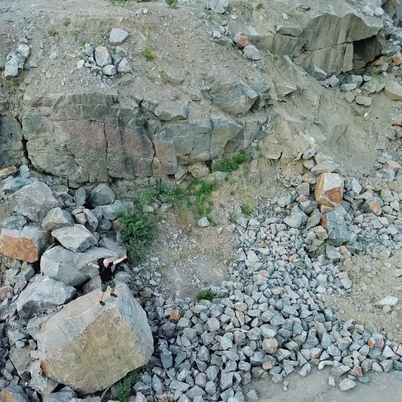 Aerial view of a young man standing on a rock. Traveler looks at the locality ahead of him. Travel concept.