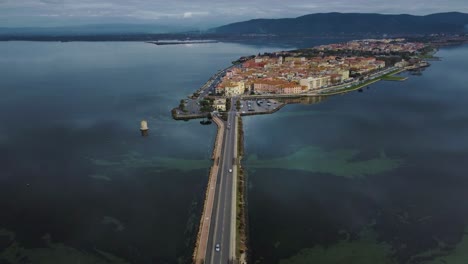 意大利托斯卡尼的奧爾貝特洛 (orbetello) 島上,靠近阿根廷山 (monte argentario) 和馬雷瑪自然公園 (maremma nature park) 的橋<unk>路上,車輛穿過<unk>湖,水面反射