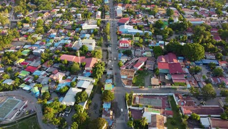 aerial drone rising over inner city view of capital dili, timor leste in southeast asia, residential houses with colorful tinned roofs, businesses and tree greenery with traffic traveling along road