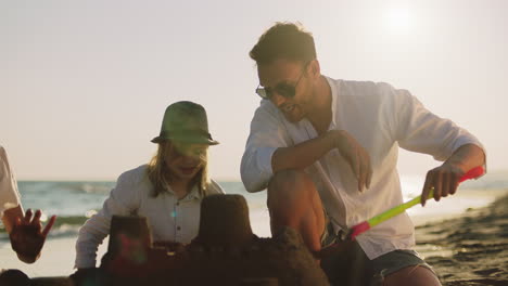 family building sandcastles on the beach at sunset