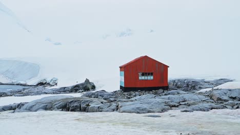 antarctic hut in antarctica at damoy point, old red shelter building surrounded by snow and ice and icy winter landscape scenery on the antarctic peninsula