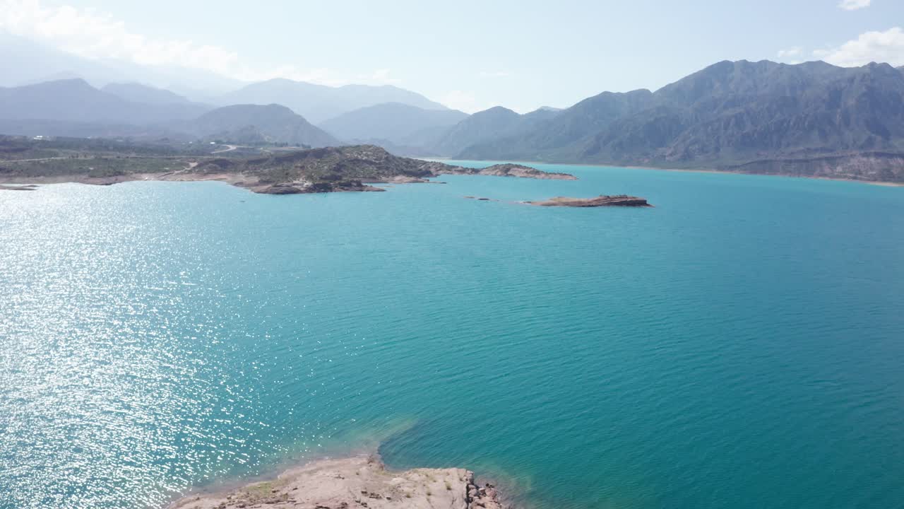 자연 한가운데 있는 청록색 푸른 물의 큰 호수 위로 날아가는 드론