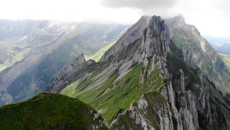 sobrevuelo aéreo sobre el lado de la cresta de schafler en appenzell, suiza con acantilados, picos de montaña y exuberante ladera verde de verano a la vista