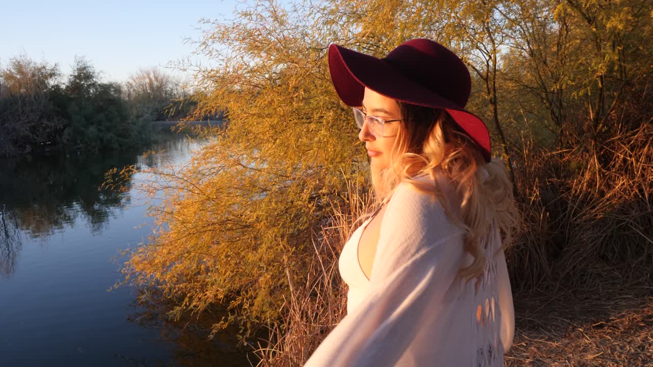 hermosa niña durante la puesta de sol junto a las aguas tranquilas del estanque
