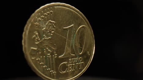 primer plano de una moneda de 10 céntimos de euro con un fondo negro que está girando