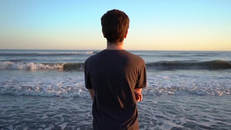 back view of a man captivated by the ocean waves during summer getaway at monte hermoso, buenos aires in argentina