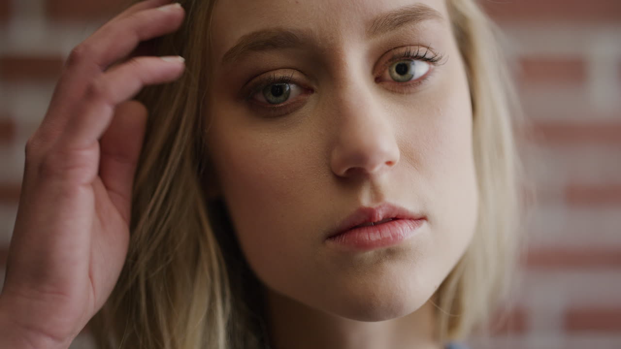 가까운 초상화 귀여운 젊은 금발 여자가 차분하게 보이고 머리카락을 통해 손을 고 느린 동작 여성적인 아름다움 피부 관리 개념