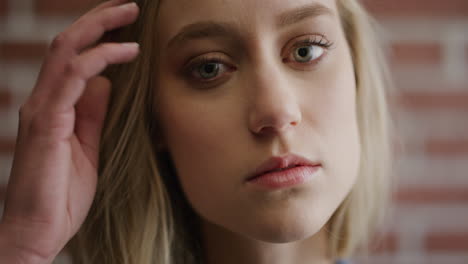 retrato de cerca de una joven rubia linda que parece tranquila corriendo con la mano a través del cabello en cámara lenta concepto de cuidado de la piel de belleza femenina