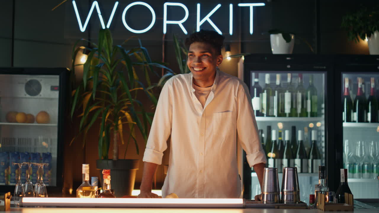 barman alegre riendo en el mostrador del bar. cabello oscuro camarero alegre esperando pedidos