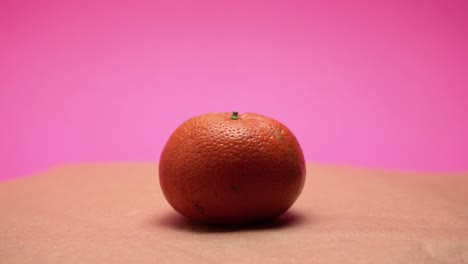 ripe mandarine, rotate on pink and old paper background 4k video colorized