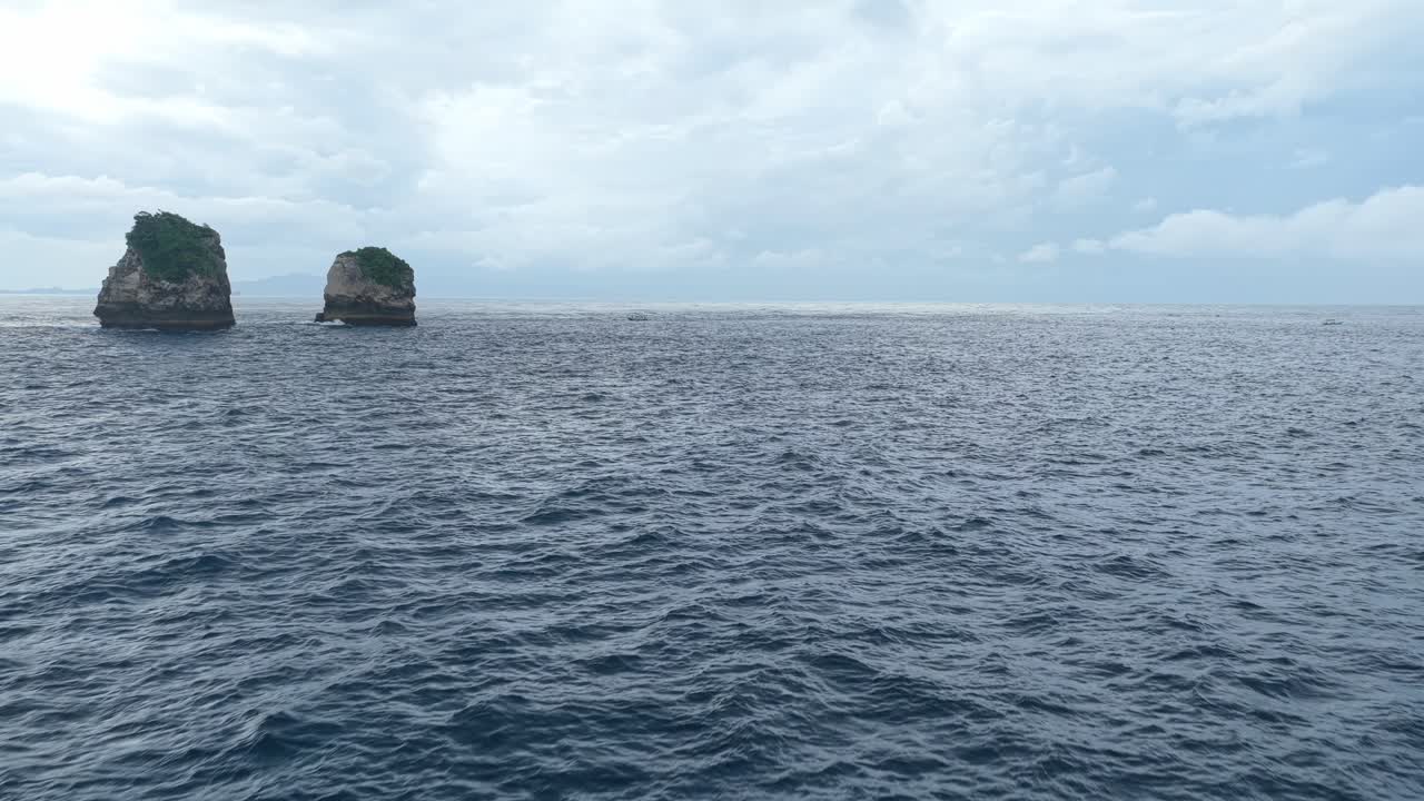 Berlayar melewati pulau-pulau berbatu di laut mendung di Bali