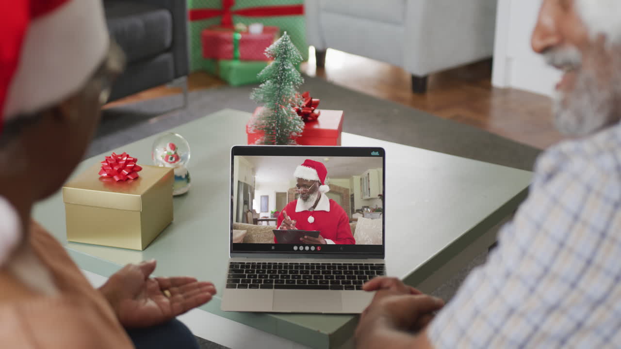 feliz pareja de ancianos afroamericanos en videollamada con santa claus en navidad
