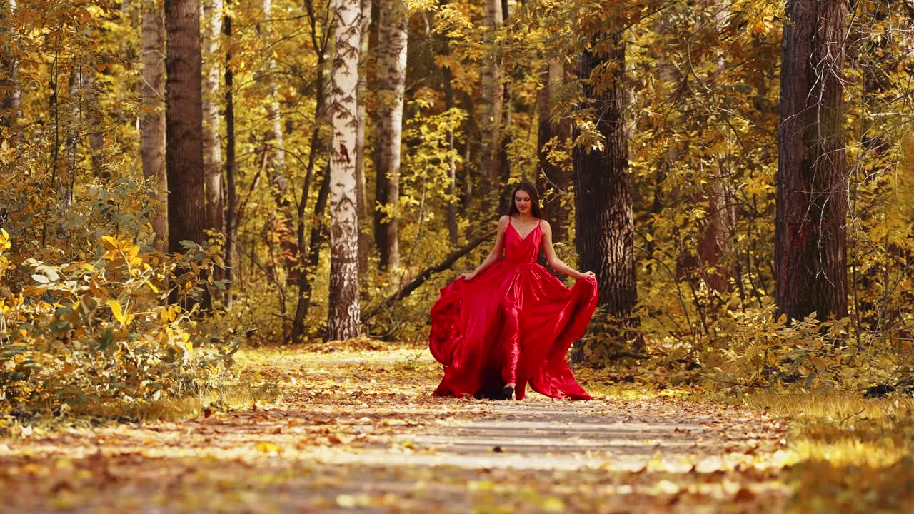 A captivating display of elegance and grace unfolds in a vibrant autumn forest, where a figure in a striking red gown moves effortlessly through a path lined with golden foliage