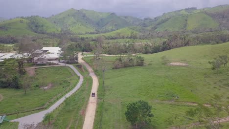 Aerial-of-a-vehicle-driving-through-the-barren-green-landscapes-of-the-Dominican-Republic