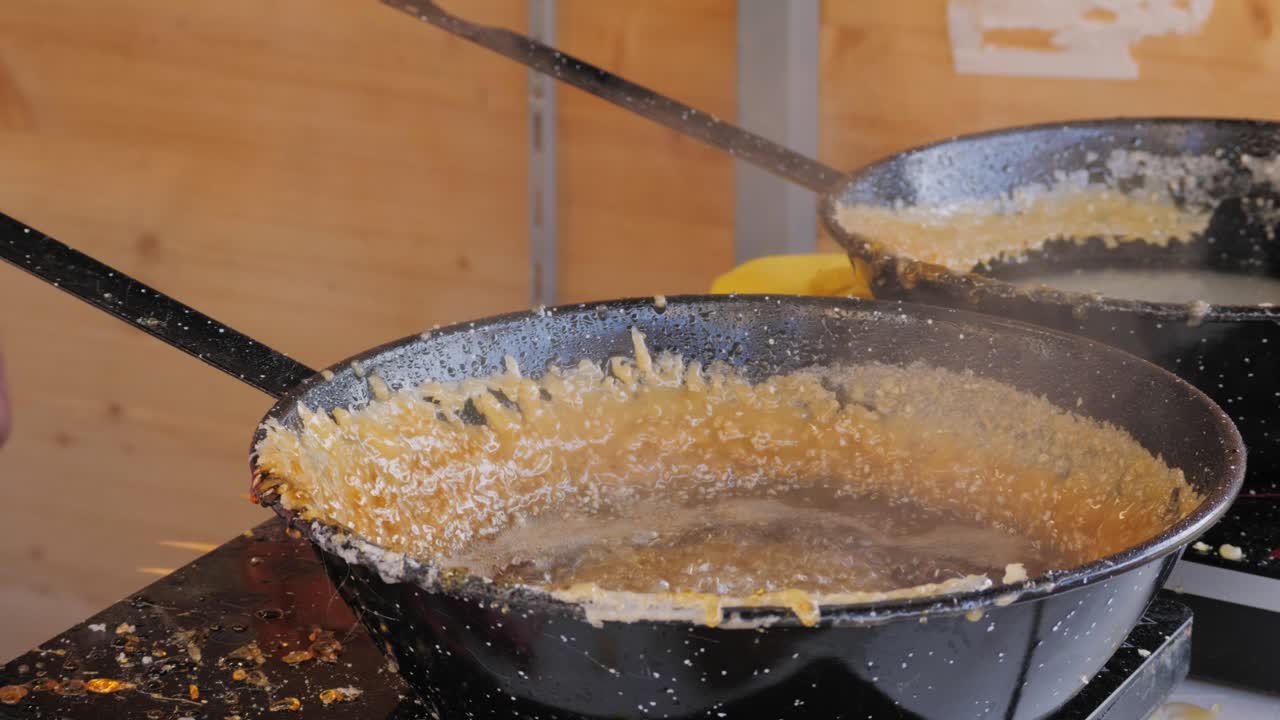 Close up of boiling sugar with bubbles turns into caramel in black pan, caramelization, chef cooking dessert in cafe, restaurant pastry food. Chinese winter sweet dessert Tanghulu. Fruits in sugar caramelized. Street food market concept