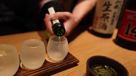 sequence of sake being poured into two glasses.