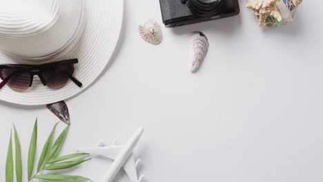 Close-up-of-sunhat,-sunglasses-and-camera-with-copy-space-on-yellow-background