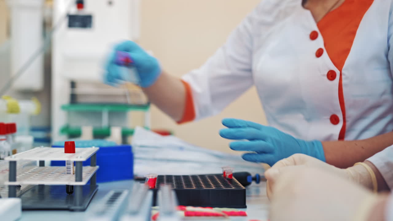 Professional laboratory technician fills vial with liquid and puts in the rack. Medical workers with test tubes of blood sample in the laboratory.