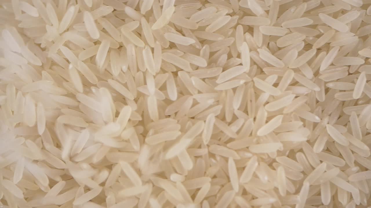 Primo piano di chicchi di riso bianco che cadono e si accumulano