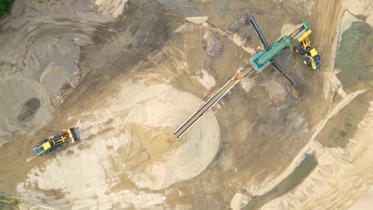 cargadora de ruedas con cucharón en piedra de carga frontal en trituradora, toma aérea de drones