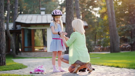 mom wears protective gloves to his daughter next to it are roller skates concept - care and protecti