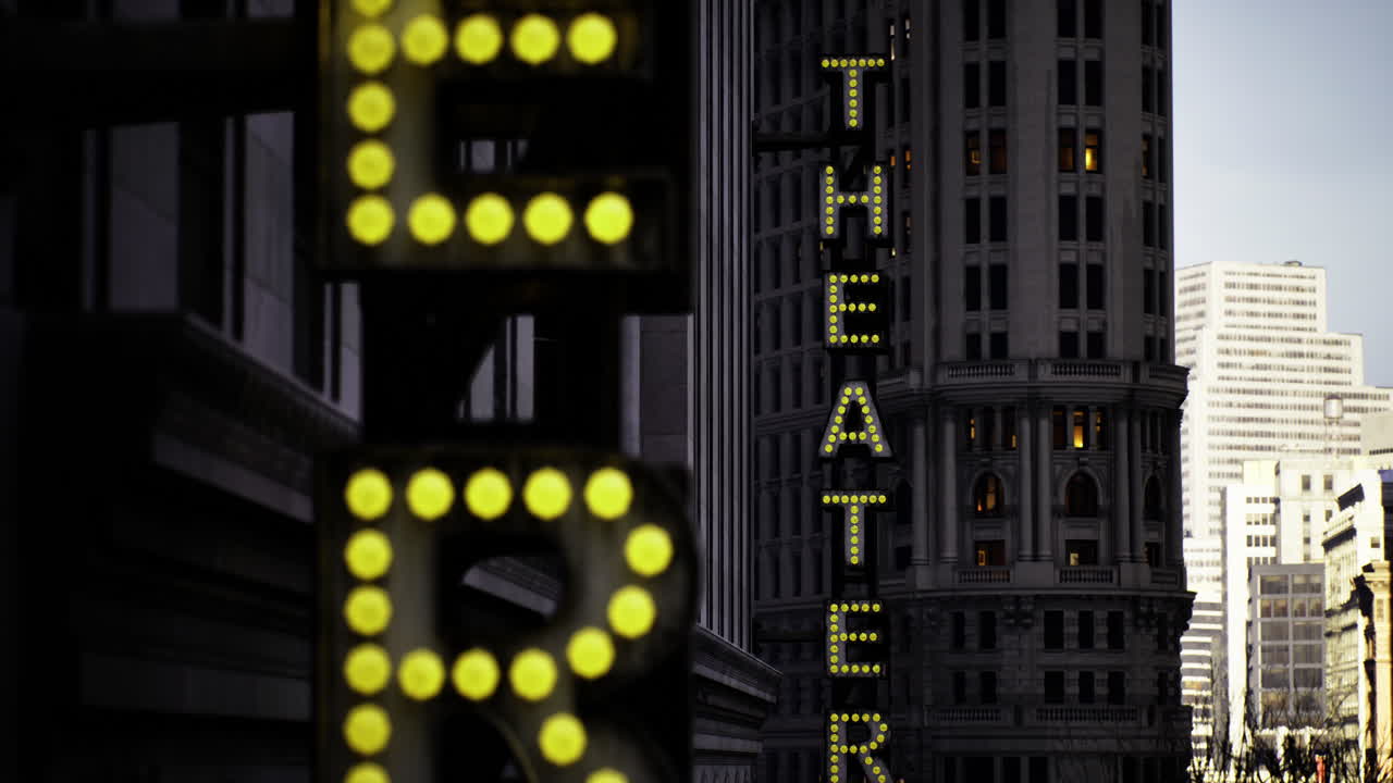 Brightly illuminated theater signs at twilight in a bustling urban setting