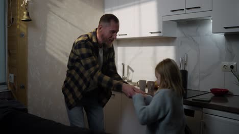 padre e hija bailando en la cocina