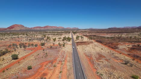 4k drone video following a camper van as it drives all alone down a very long and straight road in the australian outback in northern territory