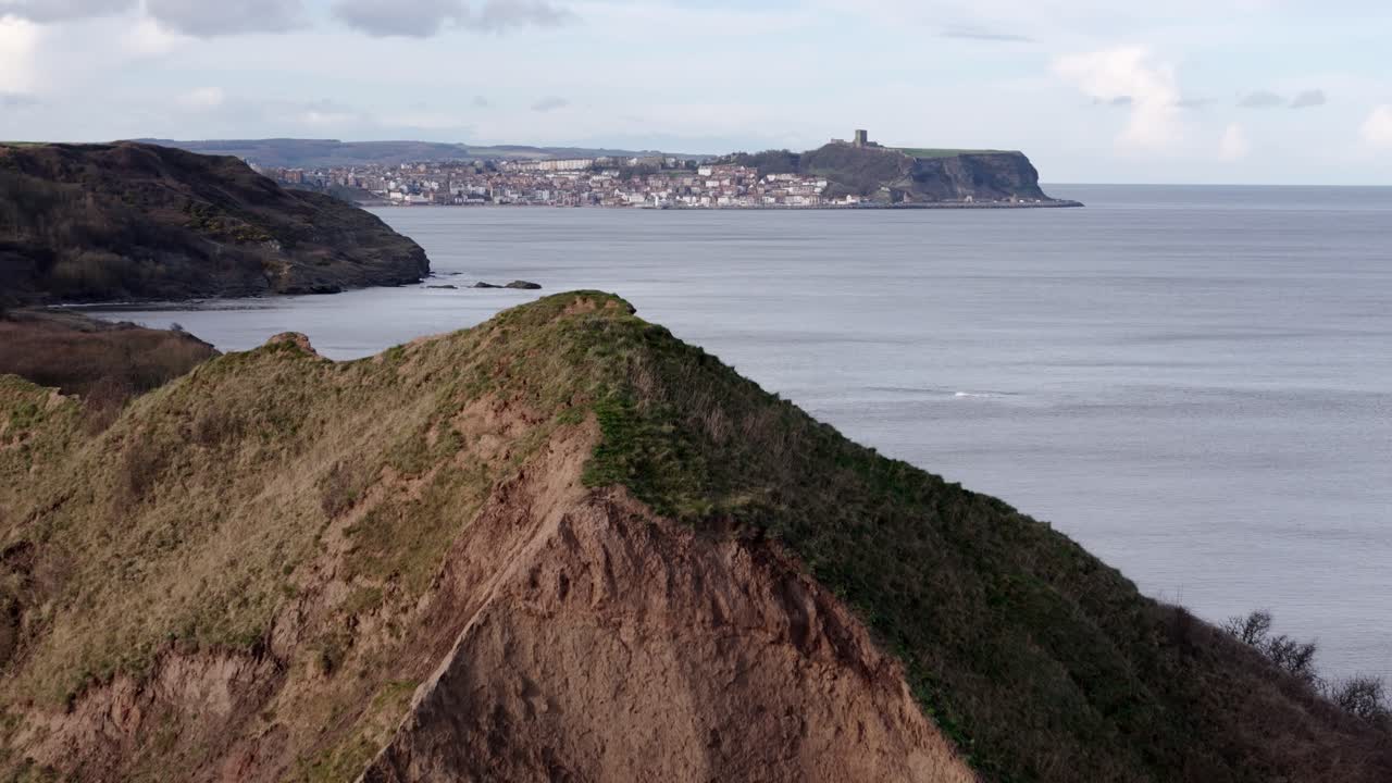 Aerial fly over footage of mountain peak with Scarborough town in the distance